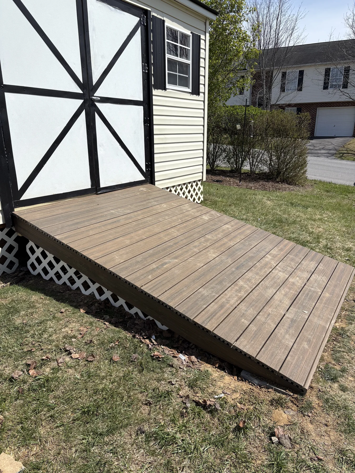 White outbuilding with black trim and a finished wooden ramp